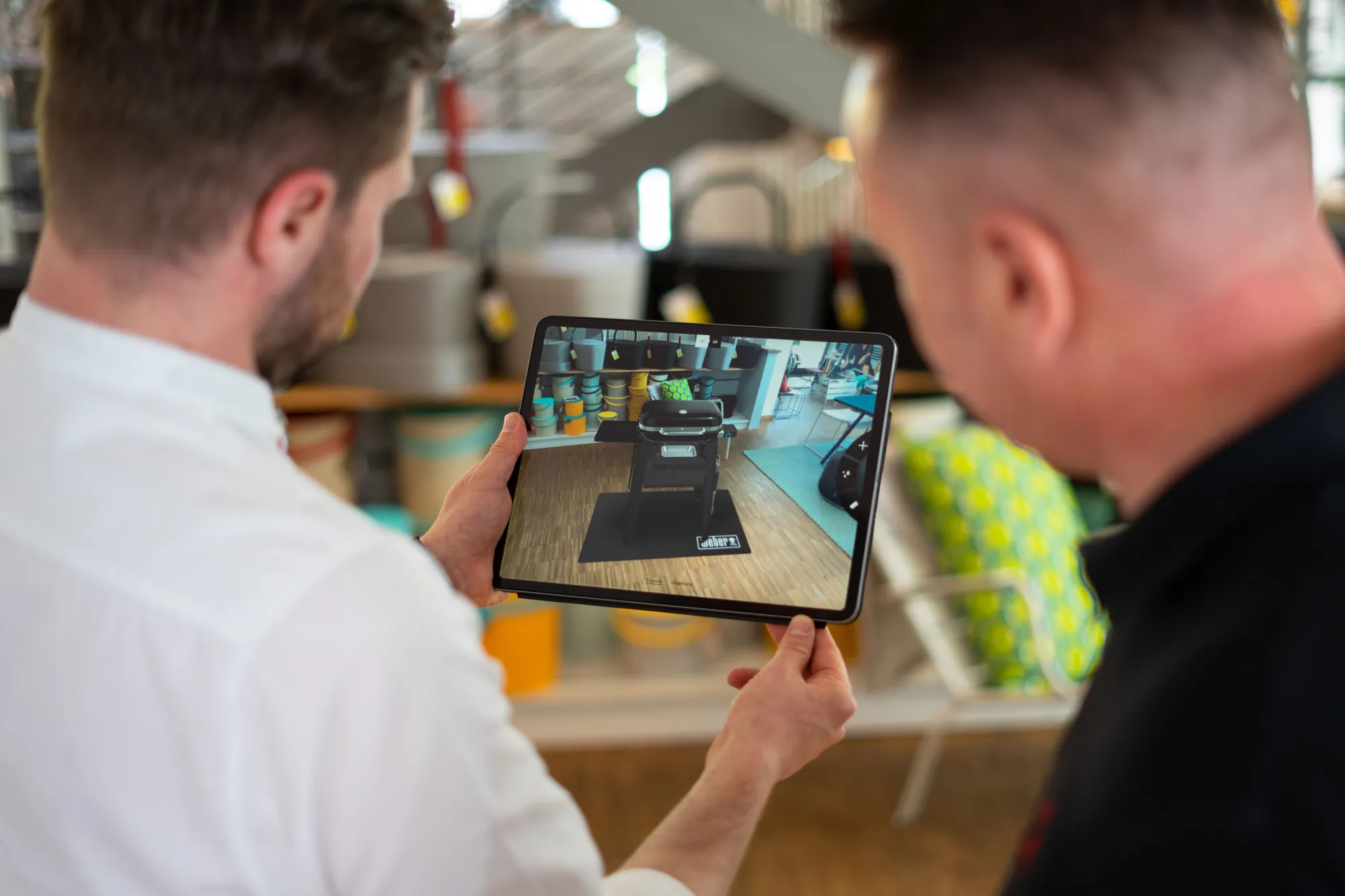 Two people look at a Weber grill in AR on an iPad